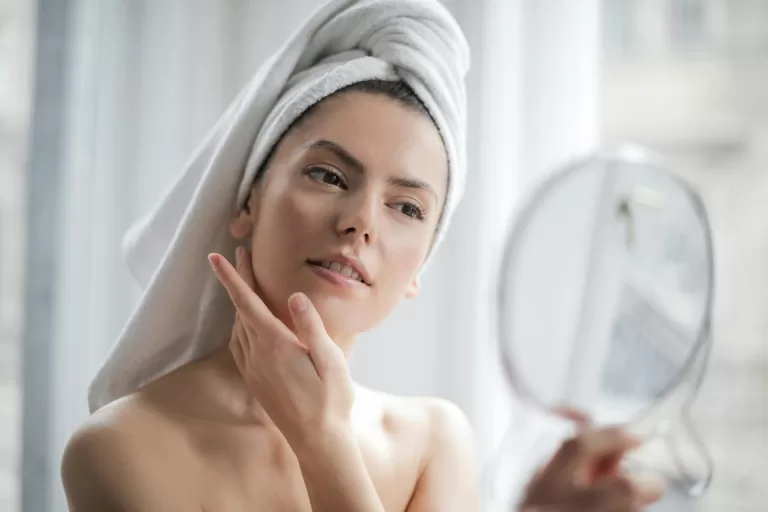 Mulher praticando cuidados com a pele em frente ao espelho