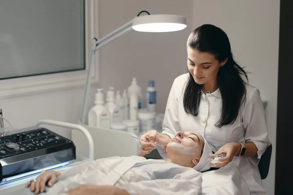 mulher da área da estética realizando procedimento no rosto de outra mulher, mostrando a área de estética e negócios lucrativa