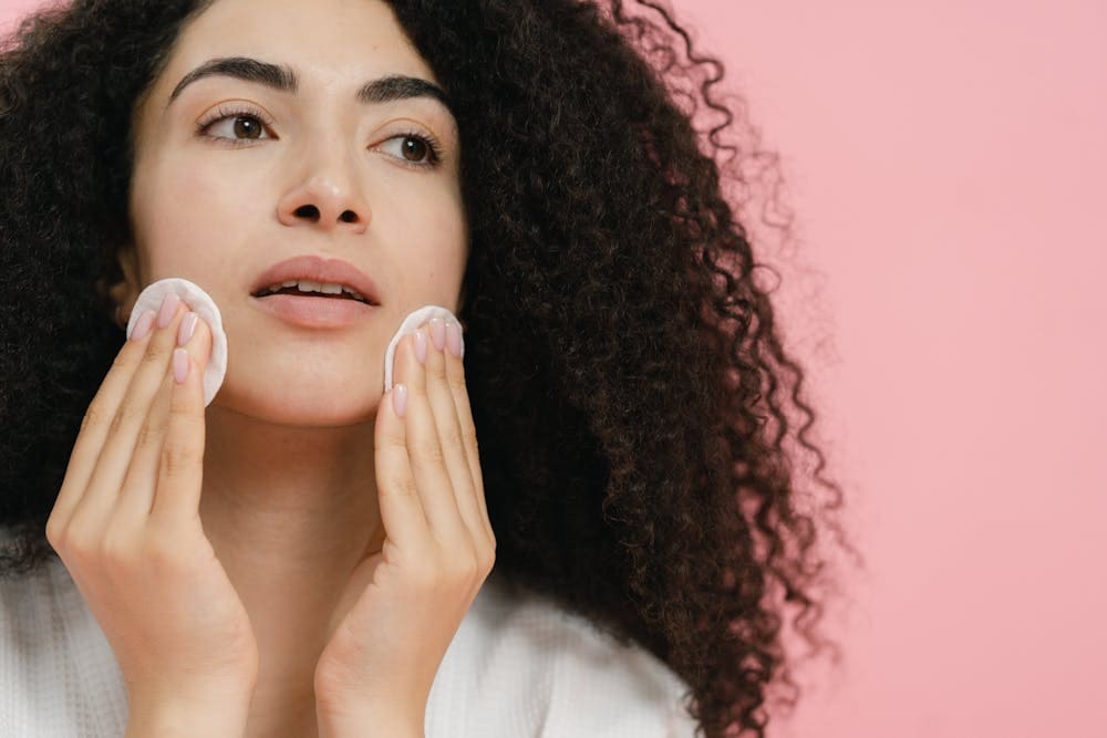 mulher limpando o rosto para praticar cuidados com a pele