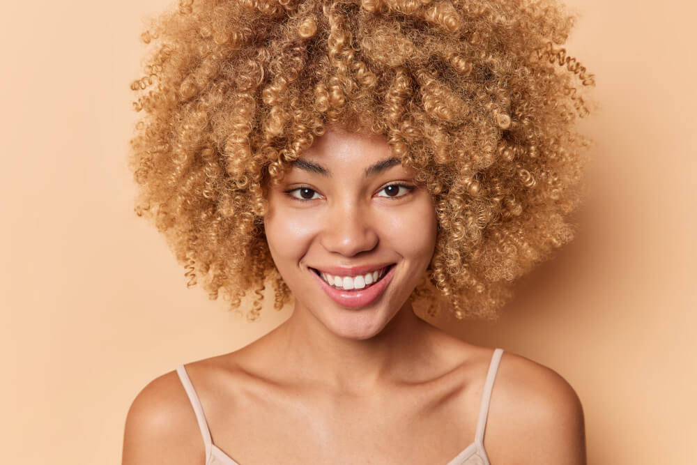 mulher de cabelo cacheado bonito e saudável feliz e sorrindo