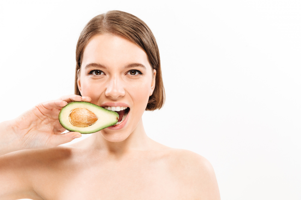 mulher comendo um abacate para melhorar a pele