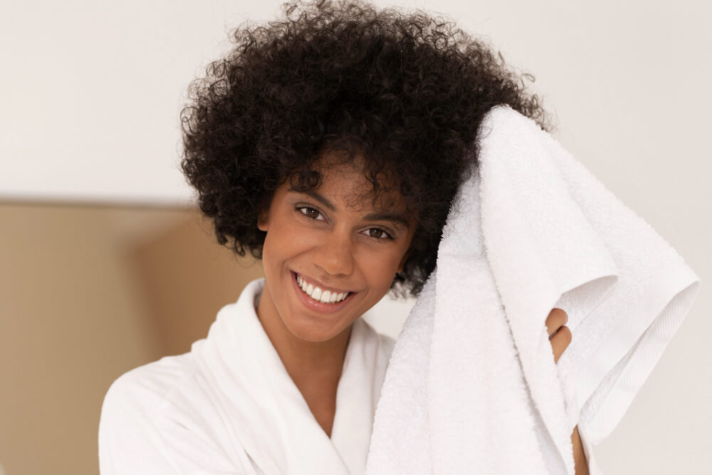 mulher de cabelos cacheados mostrando como cuidar do cabelo cacheado secando gentilmente seu cabelo