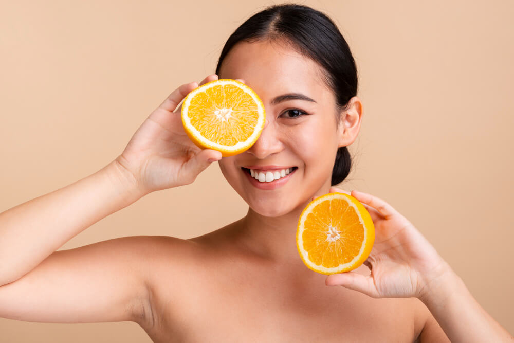 mulher segurando uma laranja com vitamina c para a pele
