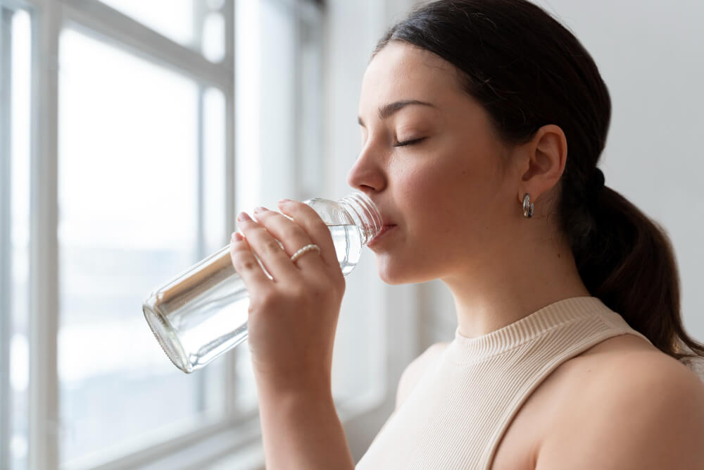 mulher tomando água para hidratar e manter a saúde de sua pele